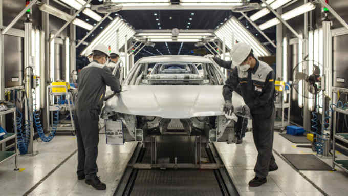 Workers clean the hood of a body frame of a Vinfast Lux A2.0 sedan in the body shop area of the automaker's factory in Haiphong, Vietnam, on Wednesday, Dec. 4, 2019. Vingroup JSC Chairman Vuong, the billionaire behind six-month-old Vietnamese auto startup VinFast, plans a feat even Toyota Motor Corp. and Hyundai Motor Co. couldn't pull off during their early days: sell a car in the U.S. Photographer: Yen Duong/Bloomberg