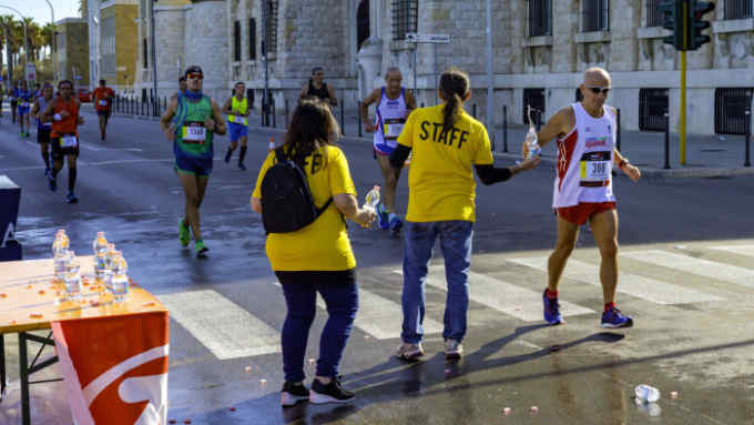 Bari, Italy - October 29, 2017: Marathon running race, runners on road, volunteer giving water on refreshment point