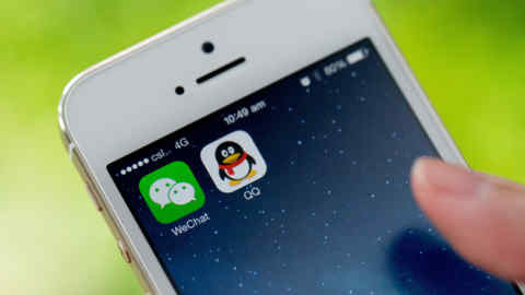 The icons for Tencent Holdings Ltd.'s messaging applications WeChat, left, and QQ are displayed on an Apple Inc. iPhone 5s smartphone in an arranged photograph in Hong Kong, China, on Wednesday, Aug. 13, 2014. The success of messaging services QQ and WeChat has helped boost Tencent’s market value to about $161 billion, making it the most valuable Internet company in Asia. Photographer: Brent Lewin/Bloomberg