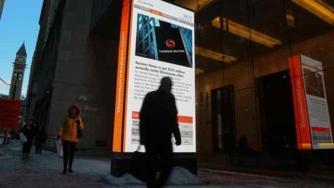 A man passes a digital billboard showing news of talks between Thomson Reuters and U.S. private equity firm Blackstone Group LP, outside the Thomson Reuters offices in Toronto, Ontario, Canada January 30, 2018. REUTERS/Chris Helgren