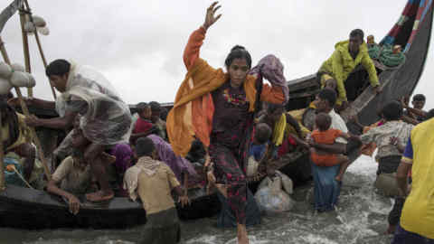 DAKHINPARA, BANGLADESH - SEPTEMBER 12: Rohingya refugees jump from a wooden boat as it begins to tip over after travelling from Myanmar, on September 12, 2017 in Dakhinpara, Bangladesh. Recent reports have suggested that around 290,000 Rohingya have now fled Myanmar after violence erupted in Rakhine state. The 'Muslim insurgents of the Arakan Rohingya Salvation Army' have issued statement that indicates that they are to observe a cease fire, and have asked the Myanmar government to reciprocate. (Photo by Dan Kitwood/Getty Images)