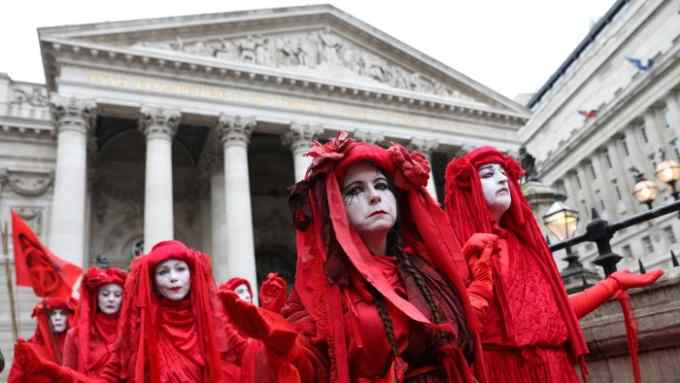 Activists dressed in red demonstrate outside of the Royal Exchange, opposite the Bank of England, during the eighth day of demonstrations by the climate change action group Extinction Rebellion, in London, on October 14, 2019. (Photo by ISABEL INFANTES / AFP) (Photo by ISABEL INFANTES/AFP via Getty Images)
