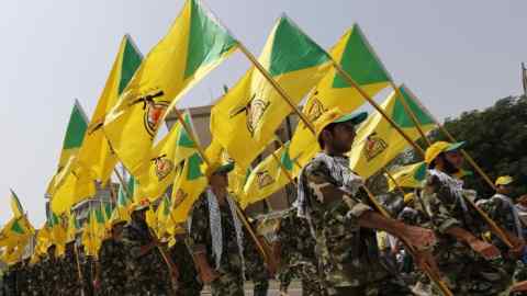 Iraqi Shi'ite Muslim men from the Iranian-backed group Kataib Hezbollah wave the party's flags as they walk along a street painted in the colours of the Israeli flag during a parade marking the annual Quds Day, or Jerusalem Day, on the last Friday of the Muslim holy month of Ramadan, in Baghdad July 25, 2014. REUTERS/Thaier al-Sudani (IRAQ - Tags: CIVIL UNREST POLITICS RELIGION) - RTR403FH