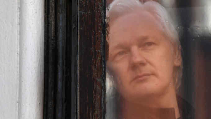 (FILES) In this file photo taken on May 19, 2017, Wikileaks founder Julian Assange peers through the window prior to speaking on the balcony of the Embassy of Ecuador in London. - A heroic campaigner for openness, or an enemy of the US state trying to avoid justice: after a decade in the limelight, WikiLeaks founder Julian Assange remains an evasive and polarising figure. (Photo by Justin TALLIS / AFP)JUSTIN TALLIS/AFP/Getty Images