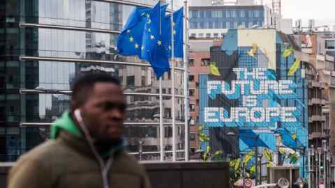 A mural reading 'The Future Is Europe' sits on display near European Union (EU) flags flying outside Berlaymont building, headquarters of the European Commission (EC), in Brussels, Belgium, on Tuesday, Jan. 28, 2020. It took 32 months, two prime ministers, and nearly 30 votes in Parliament to extricate Britain from the European Unionand the hardest part of the negotiations hasnt even started. Photographer: Geert Vanden Wijngaert/Bloomberg