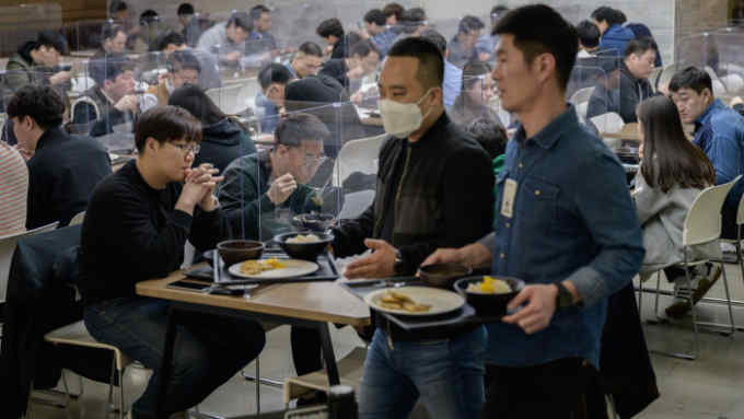 In a photo taken on April 9, 2020 employees sit behind protective screens as part of preventative measures against the COVID-19 novel coronavirus, as they eat in a cafeteria at the offices of Hyundai Card credit card company in Seoul. - Hyundai Card has implemented reduced working hours and staggered lunch breaks, while South Korea -- once grappling with the largest coronavirus outbreak outside China -- has seen a continued decline in new virus cases thanks to &quot;aggressive tests and active participation in social distancing&quot;, authorities said. (Photo by Ed JONES / AFP) (Photo by ED JONES/AFP via Getty Images)