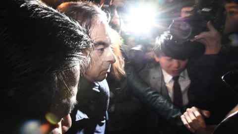 In this April 3, 2019, photo, former Nissan Chairman Carlos Ghosn, center, mobbed by journalists leaves his lawyer's office in Tokyo. Japanese prosecutors took Ghosn for questioning Thursday, April 4, 2019, barely a month after he was released on bail ahead of his trial on financial misconduct charges. (Sadayuki Goto/Kyodo News via AP)