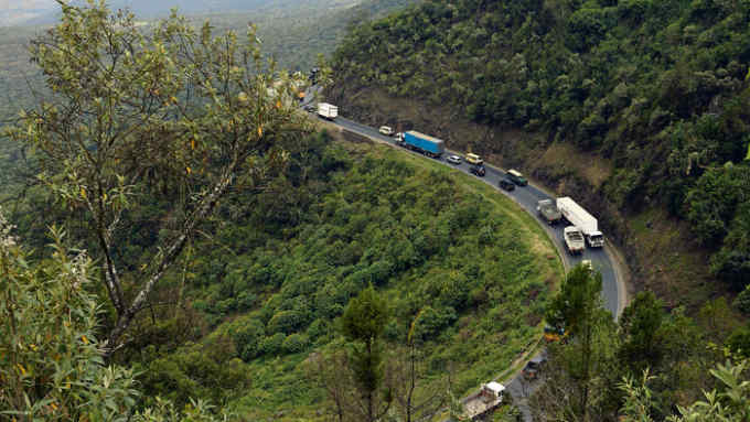 Trucks and cars drive on August 21, 2019 on a section of a road leading down the eastern escarpment of the historic Rift Valley, snaking down the cliffside leading from Limuru town perched high above the valley floor, in Kenya's central highlands now known as Kiambu county, to Maai-Mahiu - a former coal and water stop for steam locomotives, now germinated into a flourishing truck-stop at the bottom of the escarpment. - A significant number of Italian prisoners of war (POWs), captured after defeat in Ethiopia during the World War II by British and Imperial forces, were interned in the Rift Valley, East Africa, where amongst other activities, they were made to build the Mai Mahiu road, ascending some 450m up the steep easternwall from dry, hot and dusty Maai-Mahiu on the valley floor to cool, wet and green Limuru on the high plateau. (Photo by TONY KARUMBA / AFP) (Photo credit should read TONY KARUMBA/AFP/Getty Images)