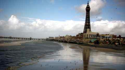 Birds in the sand as blackpool tower is reflected in the surf in blackpool.