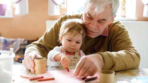 Cute little baby toddler girl and handsome senior grandfather painting with colorful pencils at home. Grandchild and man having fun together. Family and generation in love.