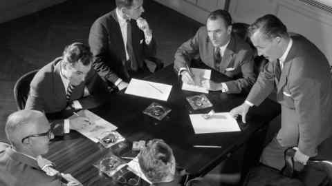 AAMX9M 1950s SIX MEN BUSINESSMEN SALESMEN IN SUITS MEETING AROUND CONFERENCE TABLE