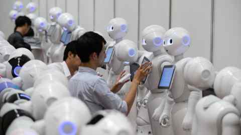 Attendees interact with SoftBank Group Corp.'s Pepper the humanoid robots during a press preview ahead of the Pepper World 2016 Summer event in Tokyo, Japan, on Wednesday, July 20, 2016. Featuring more than 20 motors and highly articulated arms, the 1.2 meter (4 foot) humanoid is capable of human-like body language. Photographer: Akio Kon/Bloomberg