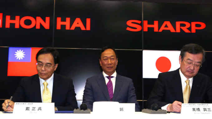 Billionaire Terry Gou, chairman of Foxconn Technology Group, center, looks on as Tai Jeng-wu, vice president of Foxconn Technology Group, left, and Kozo Takahashi, president of Sharp Corp., sign documents during a news conference in Osaka, Japan, on Saturday, April 2, 2016. Sharp Corp.’s President Kozo Takahashi and Foxconn Technology Group’s Chairman Terry Gou formally signed a merger deal on Saturday, ending a takeover drama that spanned four years of often difficult negotiations. Photographer: Buddhika Weerasinghe/Bloomberg *** Local Caption *** Tai Jeng-wu; Terry Gou; Kozo Takahashi