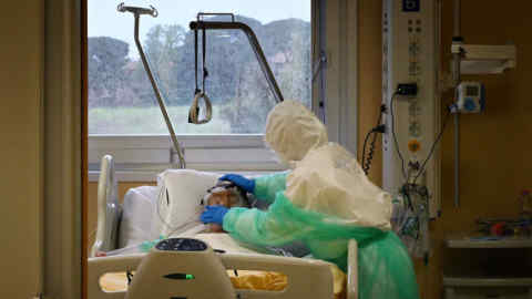 A health worker wearing protective gear takes care of a patient at the level intensive care unit, treating COVID-19 patients, at the San Filippo Neri hospital in Rome, on April 20, 2020, during the country's lockdown aimed at stopping the spread of the COVID-19 (new coronavirus) pandemic. - Italy on April 20, 2020 reported its first drop in the number of people currently suffering from the novel coronavirus since it recorded its first infection in February. (Photo by Alberto PIZZOLI / AFP) (Photo by ALBERTO PIZZOLI/AFP via Getty Images)