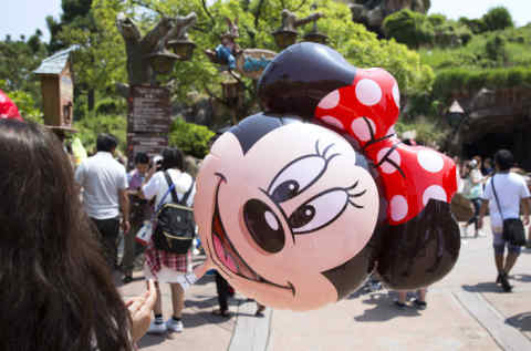 A visitor holds a Minnie Mouse balloon at Tokyo Disneyland, operated by Oriental Land Co., in Urayasu, Chiba Prefecture, Japan, on Tuesday, July 12, 2016. Photographer: Tomohiro Ohsumi/Bloomberg