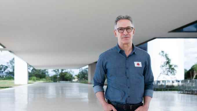 A man standing under an expansive roof of a building. He’s a middle-aged Caucasian wearing glasses and a dark-grey casual shirt