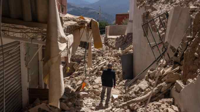 A man walks among collapsed buildings after an earthquake