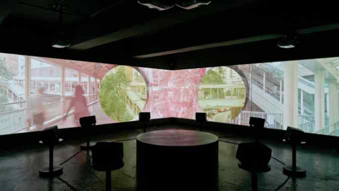 Gallery installation of a long screen showing tinted scenes from urban life