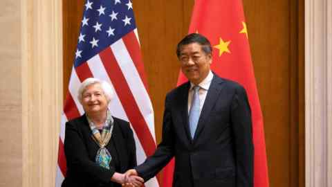Janet Yellen and He Lifeng shake hands in front of US and Chinese flags