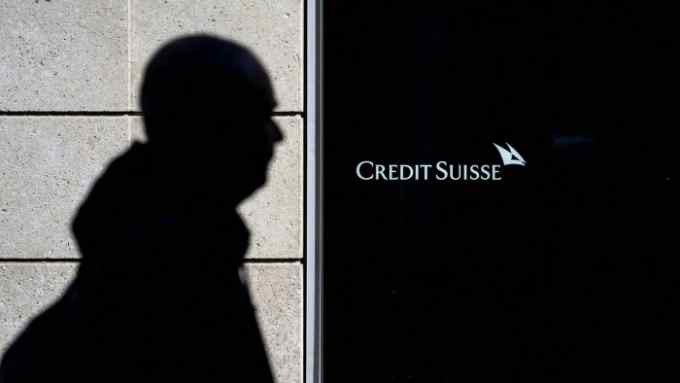 A man is seen in silhouette walking past a branch of Switzerland’s Credit Suisse bank