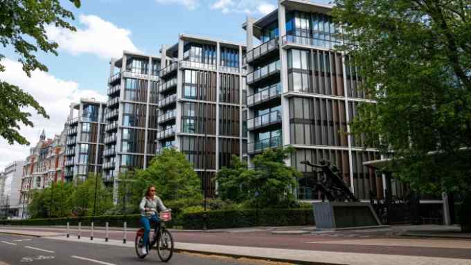 A woman on a bike cycles past a row of apartment blocks