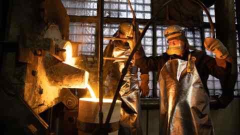 Workers fill a crucible with molten gold