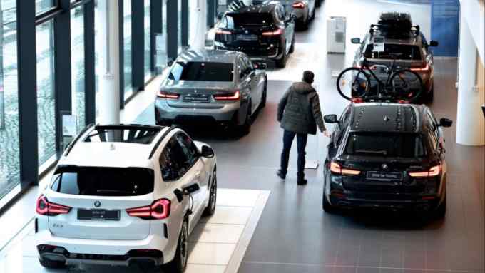 A customer looks at a BMW 5 Series Touring automobile on display at a showroom in Berlin