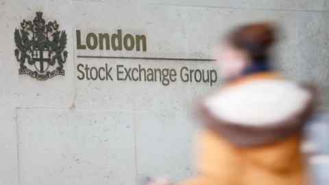 A pedestrian walks past the logo for the London Stock Exchange Group in the City of London