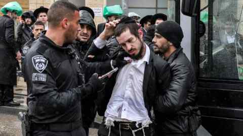 Israeli policemen try to forcibly remove ultra-orthodox Jewish protesters at a protest in Jerusalem against their conscription into the Israeli armed forces
