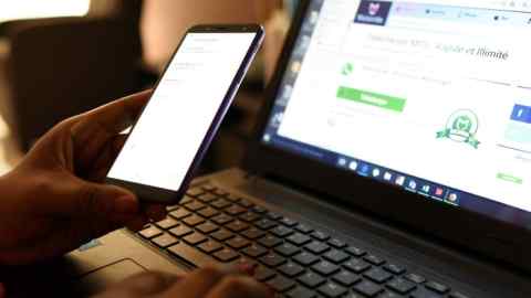 A woman uses a smartphone in front of a laptop. Almost 45m people in the UK have been targeted by scammers in the past three months, according to the telecoms regulator Ofcom