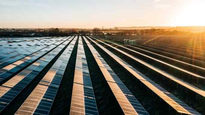 Rows of solar panels recede in parallel towards the horizon on an English solar farm