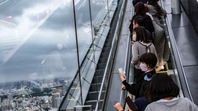 People take pictures on an escalator of an observation deck