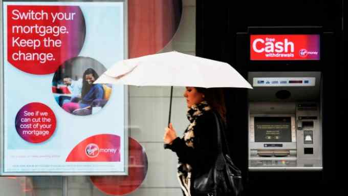 A woman walks past a Virgin Money cash machine