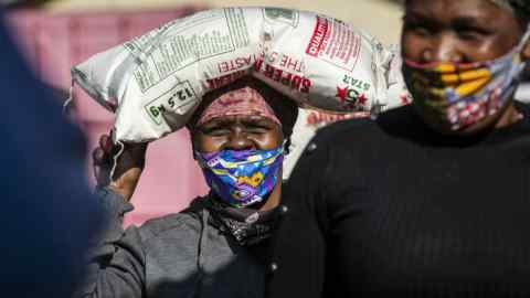 A woman carrying maize meal at a food aid distribution point in South Africa