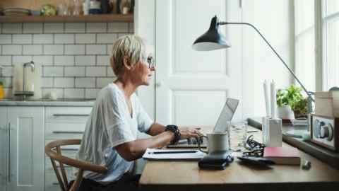 I woman in her 50s sits at a desk in her kitchen