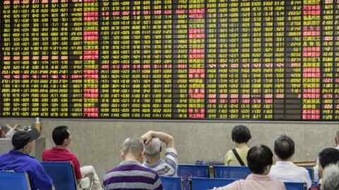 Investors sitting in front of an electronic stock board at a brokerage in Shanghai, China
