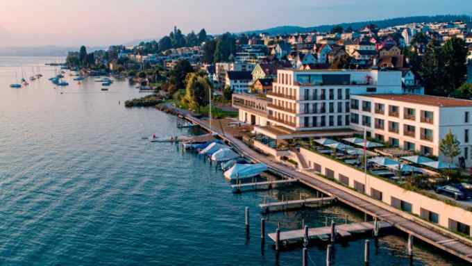 An aerial shot of the Alex Lake Zürich hotel, with its sun-kissed buildings on the shore of the lake