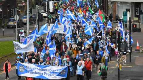 People wave Scottish flags and hold placards as they march in support of Scottish independence in Glasgow on April 20