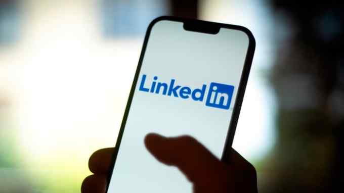 A person is seen using the LinkedIn app on a mobile device