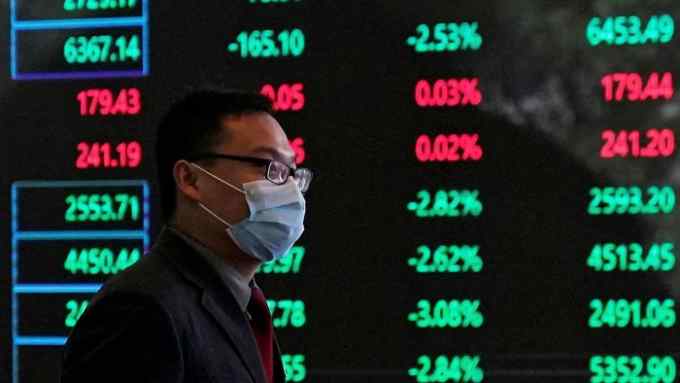 A man walks past screens in the Shanghai stock exchange