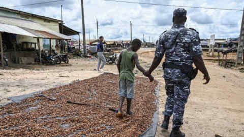 An Ivorian police officer detains a child during a crackdown on child labour in cocoa plantations