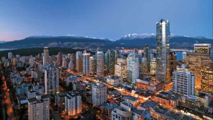 The Vancouver cityscape, with the building in which Shangri-La Vancouver is housed towering above it. There are mountains in the background