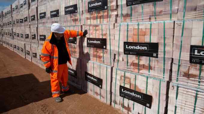 A worker inspects stacks of finished London bricks at the Forterra brickworks near Peterborough, UK
