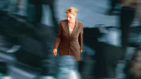 A woman in a business suit looking anxious while blurred people move around her