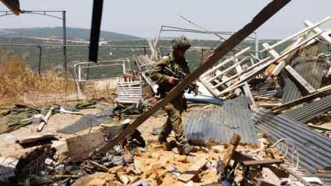 An Israeli soldier at the site of an Hizbollah anti-tank missile direct hit on a house near the Lebanon border