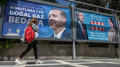 A woman walks past election posters displaying the face of Recep Tayyip Erdoğan and another with the portrait of presidential candidate, Kemal Kılıçdaroğlu