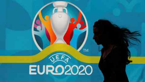 A woman walks past a poster advertising Euro 2020