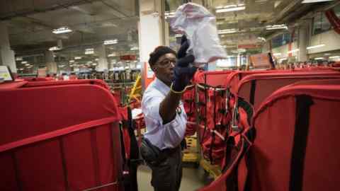 Royal Mail worker sorts mail into bags