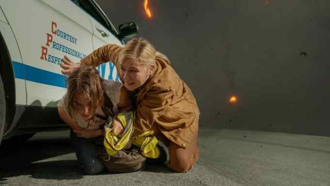 Two women shelter from a blast behind an NYPD patrol car