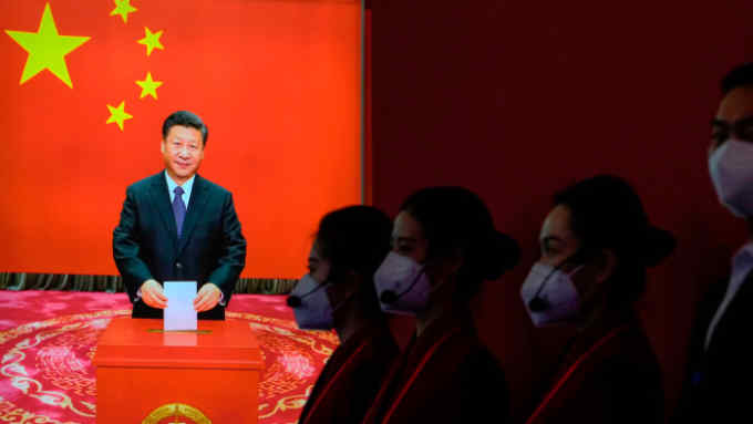 Ushers wearing face masks wait in the wings to guide visitors at an exhibition celebrating President Xi Jinping the Beijing Exhibition Hall
